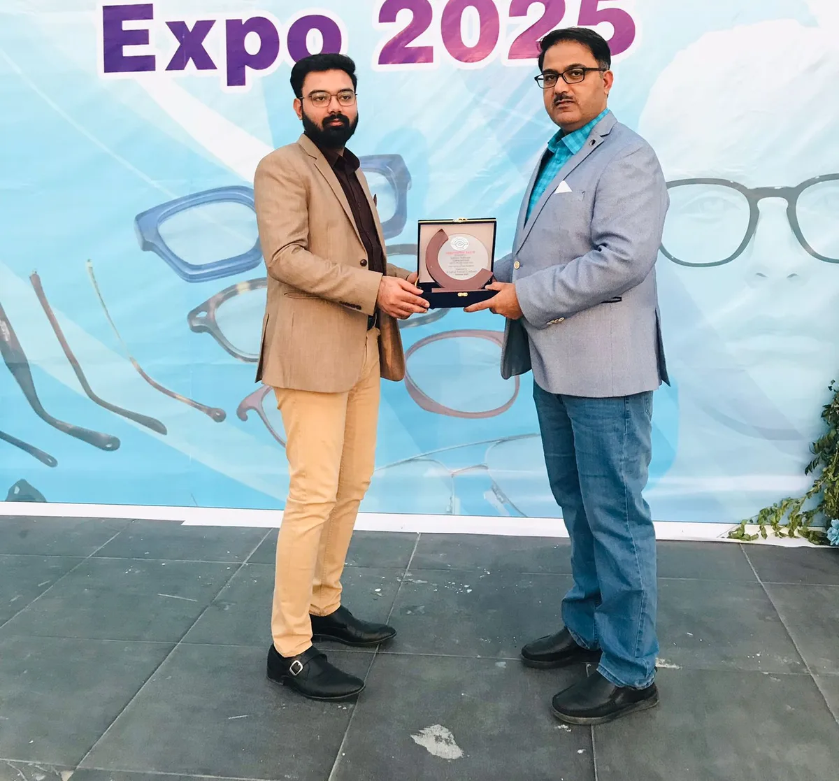 CEO Mubashar Hussain and Founder Ittyab Ur Rehman with the Opticians Association of Pakistan appreciation award in front of the official OptiPak Expo 2025 backdrop