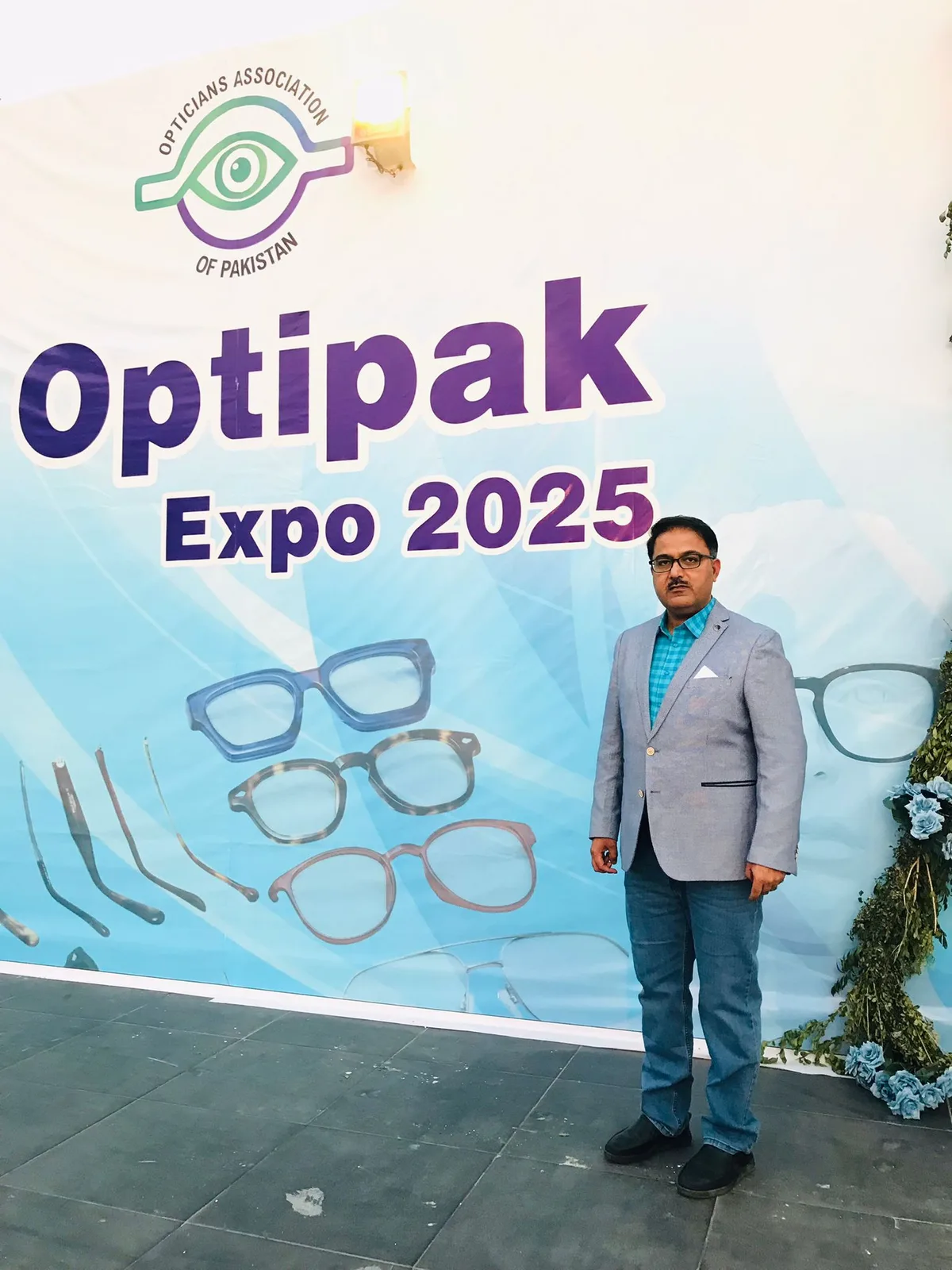 CEO Mubashar Hussain in front of the official OptiPak Expo 2025 banner of the Opticians Association of Pakistan